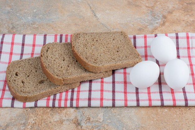 Schwarzbrotscheiben auf Tischdecke mit Eiern