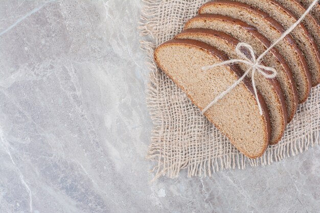 Schwarzbrotscheiben im Seil auf Marmoroberfläche