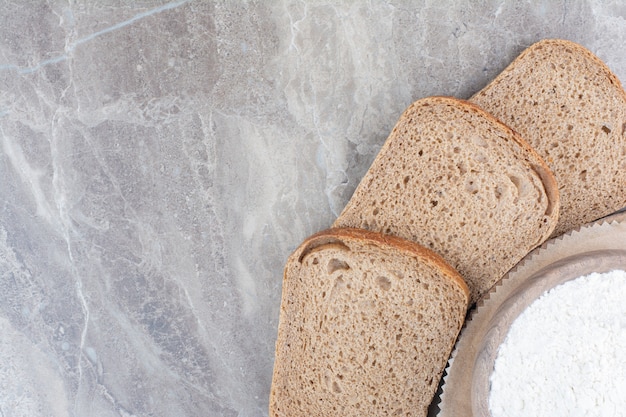 Schwarzbrotscheiben mit Mehl auf Marmoroberfläche