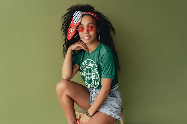 Kostenloses Foto schwarze afroamerikanerin im stylischen hipster-outfit-t-shirt und shorts auf grün