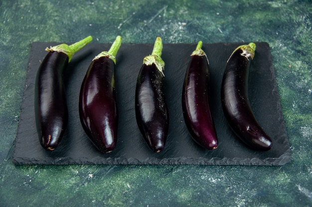 schwarze Auberginen der Vorderansicht auf dunklem Hintergrund