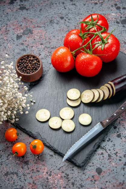 schwarze Auberginen der Vorderansicht mit blauem Hintergrund der frischen roten Tomaten