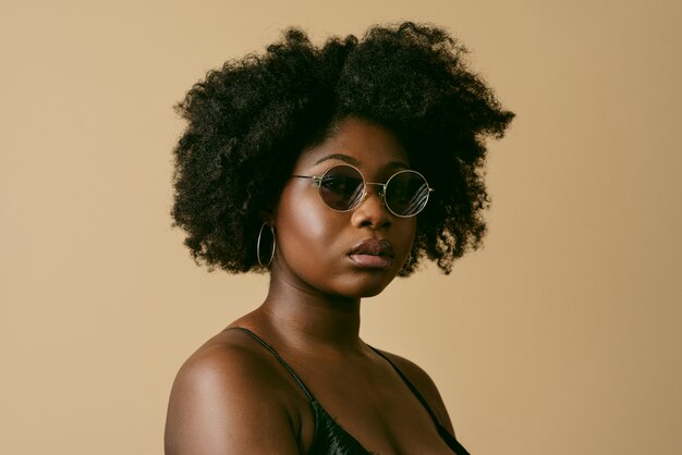 Schwarze Frau, die mit Seitenansicht der Sonnenbrille aufwirft