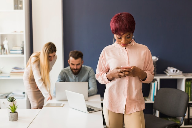 Schwarze Frau, die Smartphone im Büro verwendet