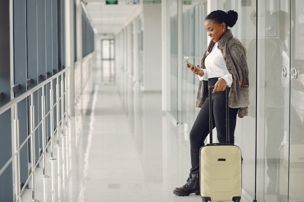 Schwarze Frau mit Koffer am Flughafen