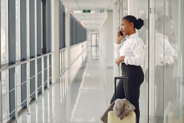 Schwarze Frau mit Koffer am Flughafen