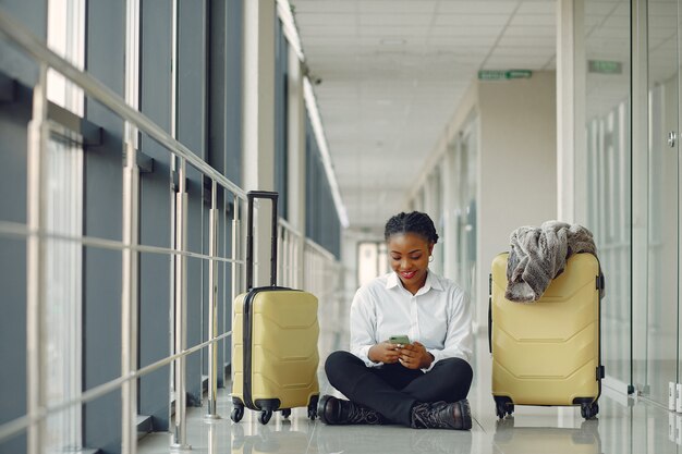 Schwarze Frau mit Koffer am Flughafen