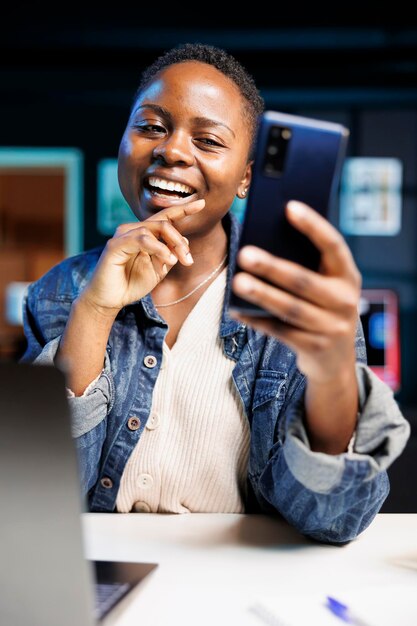 Schwarze Frau nutzt glücklich mobiles Gerät