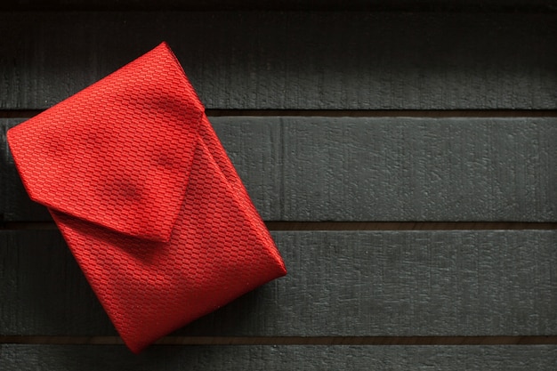 Schwarze Holzoberfläche mit roter Krawatte