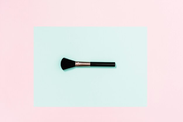 Schwarze Make-upbürste auf aquamarinem und rosa Hintergrund