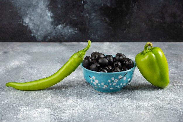 Schwarze Oliven und Paprika auf Marmortisch.