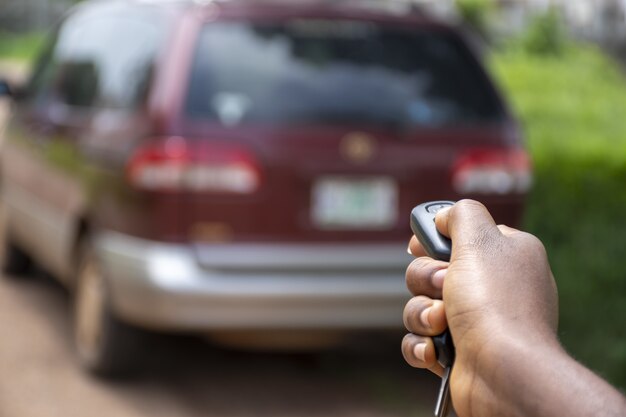 Schwarze Person, die eine Auto-Fernbedienung verwendet, um ein Auto zu entsperren