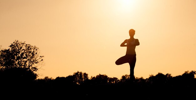 Schwarze Silhouette des Yogi-Mädchens mit den Händen vor der Brust gefaltet. Schönes Mädchen mit idealer Rückenhaltung beim Üben.