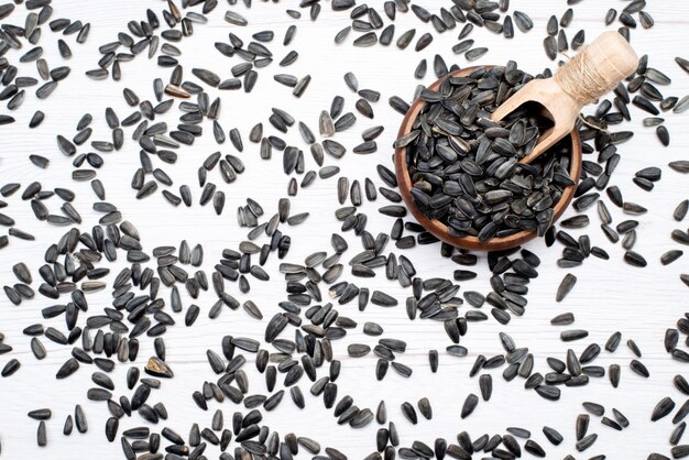 Schwarze Sonnenblumenkerne mit Draufsicht, frisch und lecker auf dem gesamten weißen Hintergrundkorn-Sonnenblumenkern-Snacköl