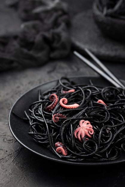 Schwarze Spaghetti auf Teller mit Tintenfisch und Stäbchen