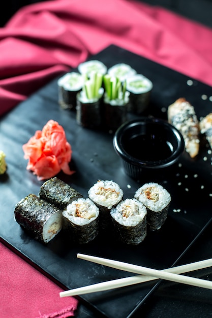Schwarze Sushirollen mit Seitenansicht und Thunfisch, serviert mit ...