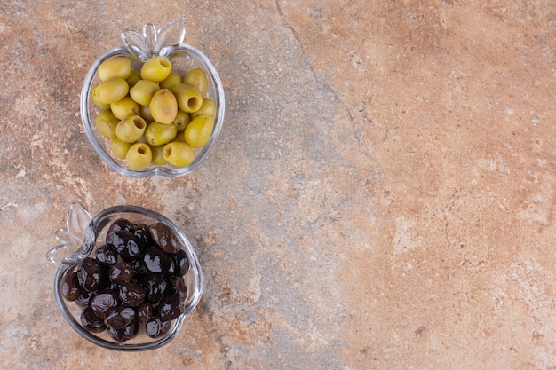 Schwarze und grüne marinierte Oliven in Glasbechern