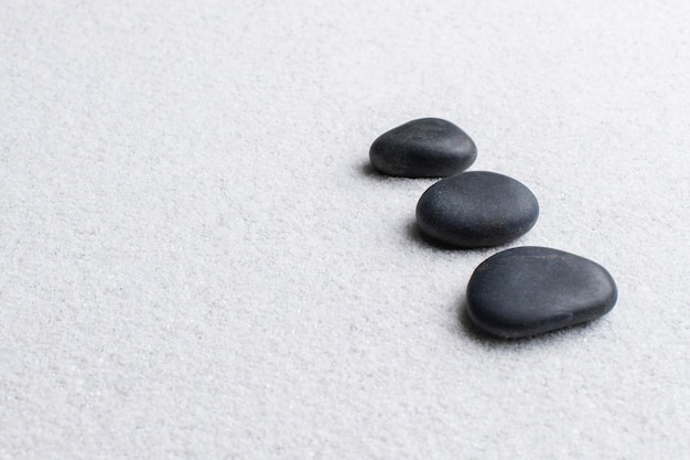 Schwarze Zen-Steine auf weißem Hintergrund im Wellness-Konzept gestapelt