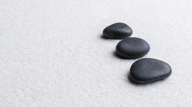 Schwarze Zen-Steine auf weißem Hintergrund im Wellness-Konzept gestapelt