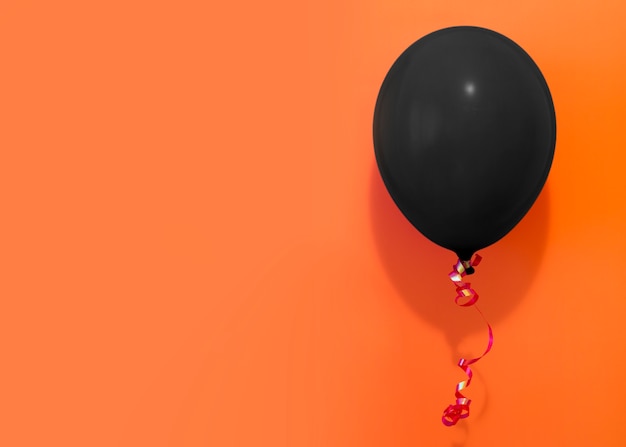 Schwarzer Ballon auf orange Hintergrund