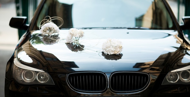 Schwarzer BMW verziert mit weißen Hochzeitsblumensträußen