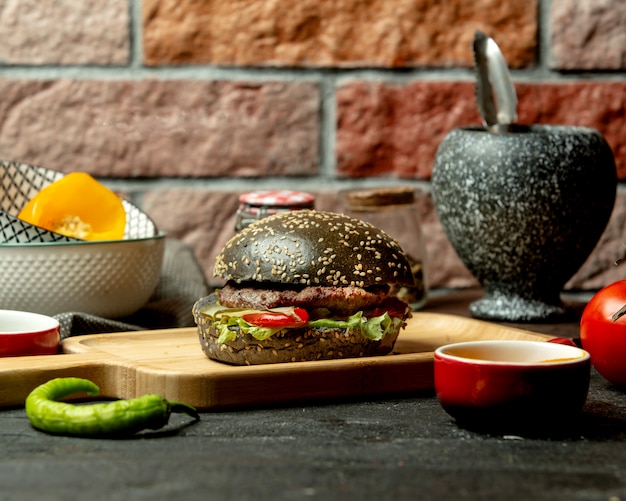 Schwarzer Burger mit Rindfleisch-Tomaten-Paprika-Salat und eingelegter Gurke