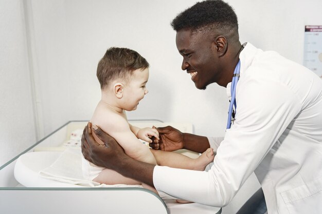 Schwarzer Doktor. Baby in Windel. Afrikaner mit Stethoskop.
