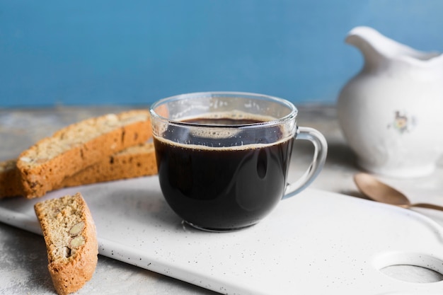 Schwarzer Kaffee im Glas neben Brotscheiben mit Samen