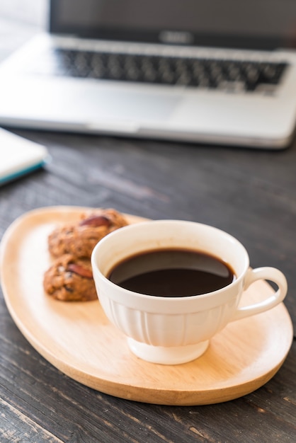 schwarzer Kaffee und Kekse mit Laptop und Notizbuch