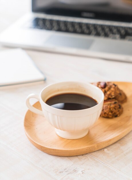 schwarzer Kaffee und Kekse mit Laptop und Notizbuch