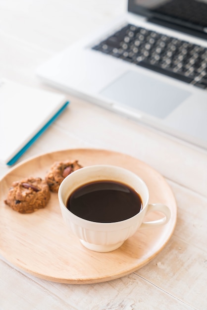 schwarzer Kaffee und Kekse mit Laptop und Notizbuch