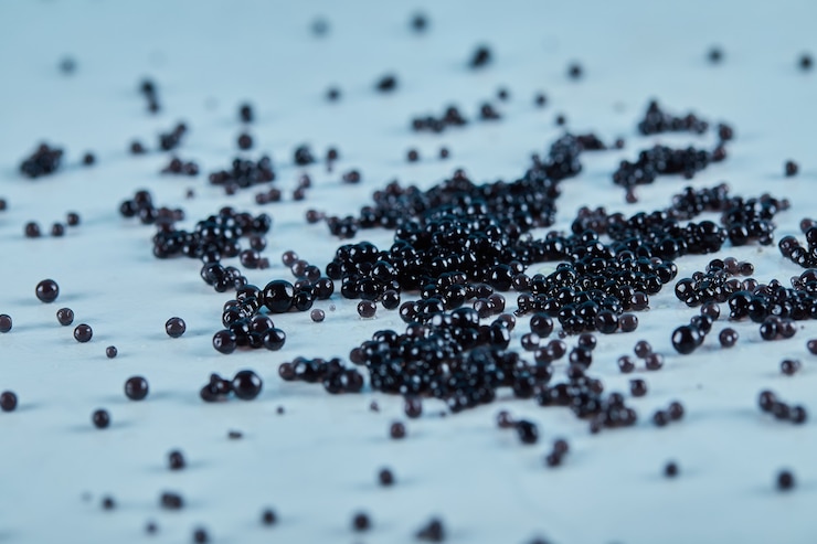Kostenlose Foto schwarzer kaviar auf dem blauen tisch verstreut.