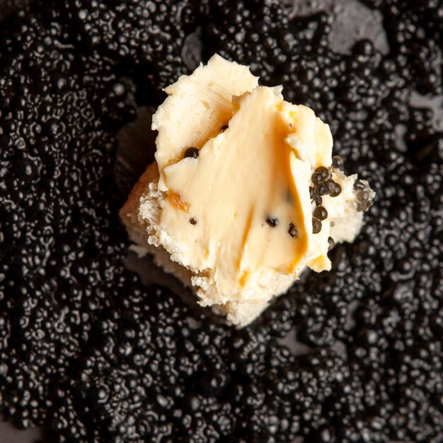 Schwarzer Kaviar der hohen Winkelansicht mit Brot und Butter auf dunklem Hintergrund.