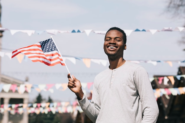 Schwarzer Mann, der amerikanische Flagge und das Lachen hält