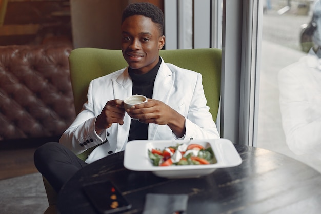 Schwarzer Mann, der in einem Café sitzt und einen Gemüsesalat isst