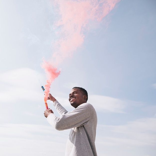 Kostenloses Foto schwarzer mann, der rote rauchbomben hält