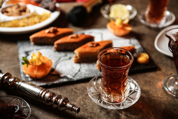 Kostenloses Foto schwarzer tee im armudu-glas mit verschiedenen süßigkeiten auf dem tisch