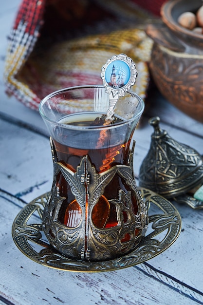 Schwarzer Tee in einer traditionellen Glasschale und Kekse auf blauem Holztisch