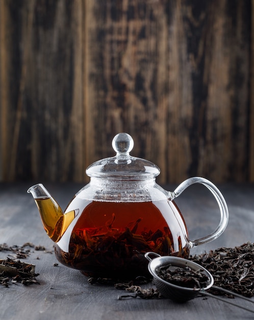 Schwarzer Tee mit trockenem Tee in einer Teekanne auf Holzoberfläche