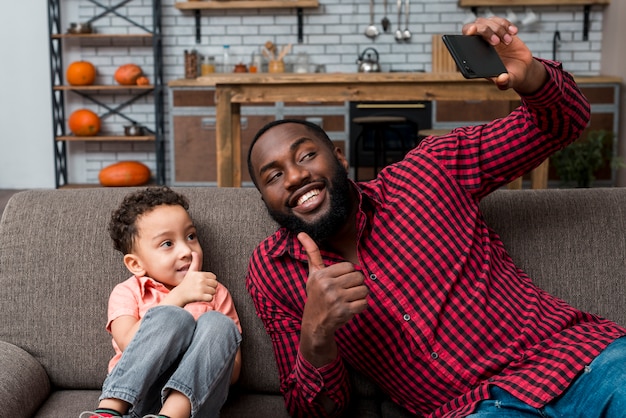Schwarzer Vater und Sohn, die das selfie sich zeigt Daumen nimmt