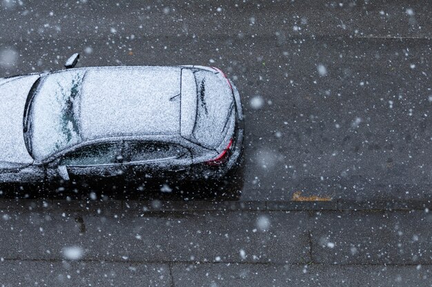 Schwarzes Auto auf der Straße unter dem Schnee im Frühjahr in Neuzagreb, Kroatien