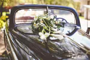 Kostenloses Foto schwarzes auto der weinlese verziert mit callas für eine hochzeitsreise