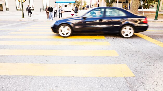 Schwarzes Autofahren auf Straße mit gelbem Zebrastreifen