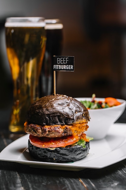 Kostenloses Foto schwarzes fleisch burger tomaten salat cheddar käse seitenansicht