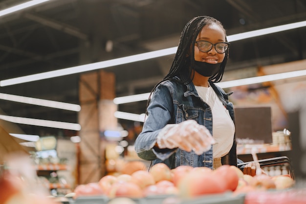 Schwarzes Mädchen in einer Maske kaufen ein Essen