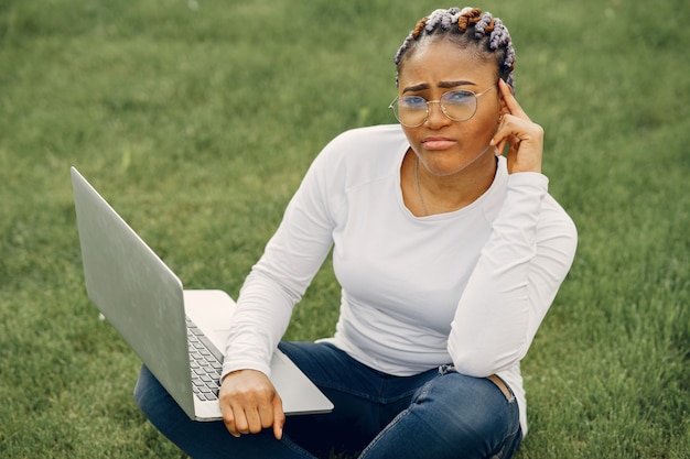 Schwarzes Mädchen in einer Sommerstadt mit Laptop