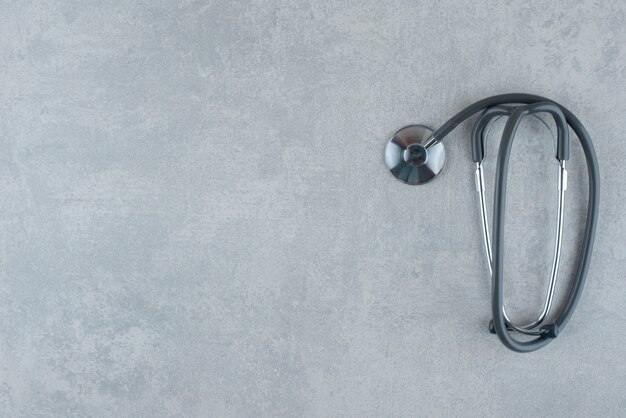 Schwarzes medizinisches Stethoskop auf grauem Hintergrund. Foto in hoher Qualität