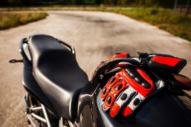 Schwarzes Motorrad mit dem Reiten von roten Handschuhen