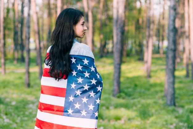 Schwarzhaarige Frau eingewickelt in der Flagge von USA