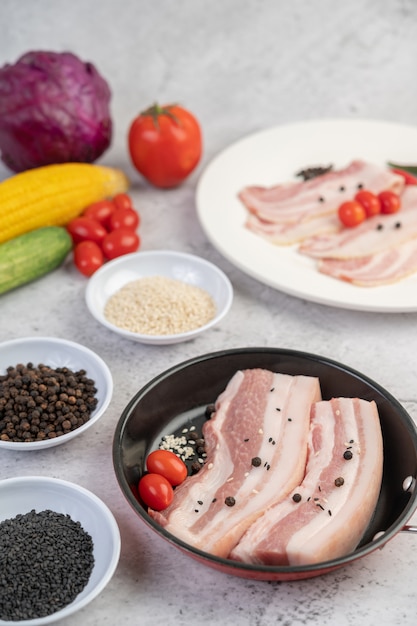 Schweinebauch in einer pfanne mit pfeffersamen tomaten und gewürzen